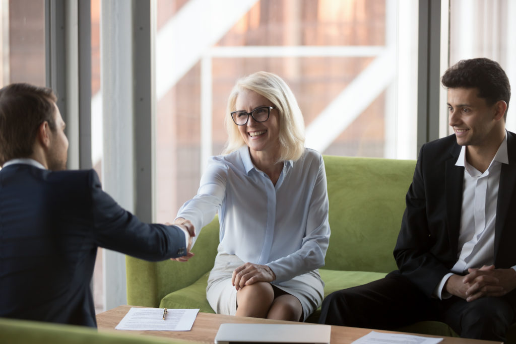 Smiling business woman executive manager shaking hands with company partner greeting each other and expressing regard. 