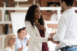 Happy female employee gets rewarded for professional achievement, shaking hands with boss,