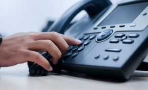 close up employee man hand point to press button number on office telephone