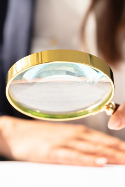 person using magnifying glass to examine documents