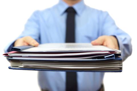 A photograph of someone holding a binder full of paper.