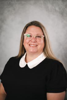 Portrait of a woman wearing glasses with a gray background